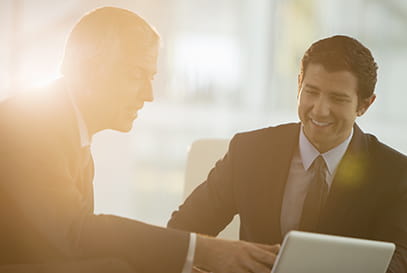 Older businessman and younger man looking at tablet